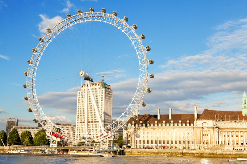 View of the London Eye from across the River Thames on a sunny day.